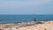 Lonely caucasian fisherman standing on rocky seashore and throwing fishing rod into the sea. Elderly man fishing on sea