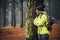 Lonely caucasian middle age woman standing in the forest and look the beautiful wood around her - concept of alternative trekking