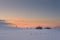 Lonely chalet on snowy meadow at winter sunset