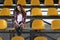 Lonely cheerleader girl sitting in stands and smiles sweetly.