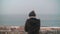 Lonely child looking at the ocean and coastal resort town of Nazare, Portugal