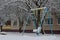 Lonely child on swing street, the Playground, in winter under the snow, in a city yard.