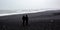 A lonely couple look out at the Black beach of Iceland.