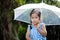 Lonely cute asian little girl with umbrella in rain