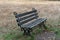 A lonely dark bench in the park clearing