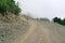 Lonely desert road in the mountains in the fog walking travelers