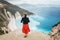 Lonely female enjoying Myrtos Beach viewpoint - unique turquoise water landmark seashore with bright white pebbles often