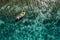 A lonely female in a straw hat smiling, relaxing lying floating in a kayak on the turquoise Adriatic Sea waves. Aerial coastal top