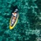 A lonely female in a straw hat smiling, relaxing lying floating in a kayak on the turquoise Adriatic Sea waves. Aerial coastal top