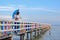 Lonely female tourist with umbrella relaxing and watching view on colorful wooden bridge at sea viewpoint