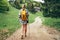 Lonely female with yellow backpack walking by mountain path with trekking poles to mount refuge hut in Slovakia, Mala Fatra region