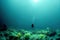 A lonely figure of a diver and a diver underwater view of the rocky ocean floor.