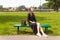 Lonely girl in a dress on a park bench, enjoys a vacation.