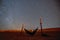 Lonely hammock next to dunes on Sahara desert with amazing starry sky above, Morocco