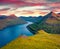 Lonely hiker admiring spectacular sunset on Faroese fjords in the outskirts of Funningur village. Unbelievable morning view of Eys