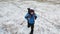 Lonely hiker walks across an endless snow field.