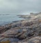 .Lonely house in foggy haze on a rocky shore of the north sea