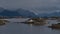 Lonely house with white facade located on tiny island on the coast of village HenningsvÃ¦r, Lofoten, Norway with mountains.