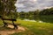 Lonely isolated bench against lake and green trees. Park.