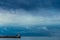 Lonely lighthouse with a red lantern on a background of rainy blue clouds