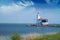 Lonely lighthouse stands on the spit in the sea near the village