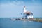 Lonely lighthouse stands on the spit in the sea near the village