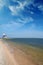 Lonely lighthouse stands on the spit in the sea near the village