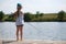 Lonely little child fishing from wooden dock on lake