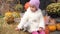 Lonely little girl scared sitting on the street Halloween with pumpkins on the background