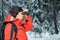 Lonely lost tourist man in winter forest with binoculars looking