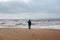 Lonely man figure walking near wild waving sea on coastline, north beach landscape