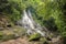 A lonely man in a red dress sitting and climbing in a waterfall