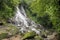 A lonely man in a red dress sitting and climbing in a waterfall