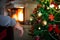 Lonely man`s hand in front of the fireplace with christmas tree.