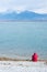 Lonely man sitting on the lakeshore, admiring the nature. Unrecognisable person