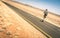 Lonely man walking along the road at namibian african desert