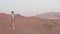 lonely man walking in empty lifeless desert, strolling on sand dunes in sunset, full-length portrait