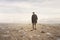 Lonely man walks towards an unknown destination in a desert