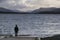 Lonely man in wild landscape mountains and lake in winter storm clouds at Loch Lomond Scotland