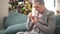 Lonely mature woman drinking tea while sitting on the couch. An elderly pensioner with a short haircut and gray hair and