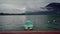 Lonely mint boat moored to promenade of Lake Annecy on fog mountains background in rainy day