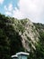 Lonely modern little white building in front of the huge rock mountain on blue sky background, vertical style.