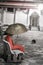 Lonely monk with umbrella sitting on bench inside buddhist temple yard with black cat in the background