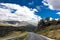 Lonely and moody road with clouds and an interesting light. Mountain road with dramatic colourful sky. Journey, outdoor, travel