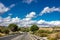 Lonely and moody road with clouds and an interesting light. Mountain road with dramatic colourful sky. Journey, outdoor, travel