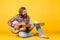 a lonely musician. cheerful handsome mature man playing guitar and smiling while sitting on yellow background. Portrait