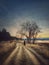 Lonely nomad person walking a country road. Moody and calm evening scene. Wanderer silhouette on trail. Cold season idyllic rural