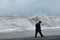 Lonely old man walking along coast, back view.