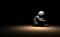 A lonely person in the dark. Sitting on the floor, hugging his knees to his chest. Regret and despair.