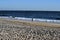 Lonely person walking along beach with surf